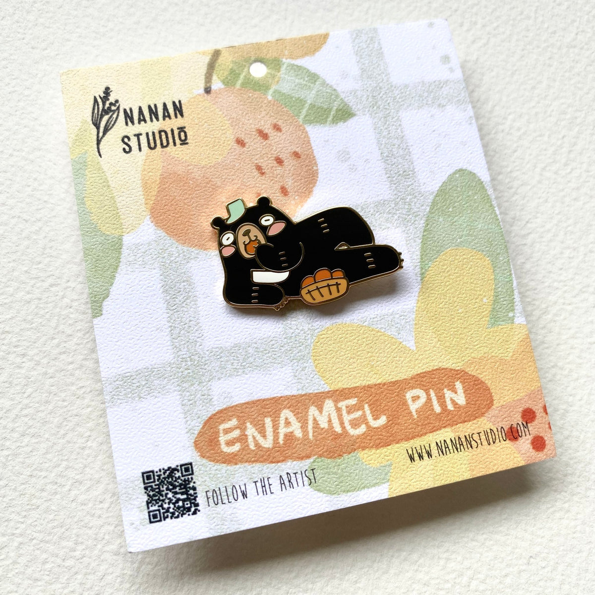 Principal Bear enamel pin on its backing card, photographed at an angle to show the gold outlines