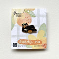 Principal Bear enamel pin, a Formosan black bear lying on his side eating a snack beside a basket of orange fruit, on a Nanan Studio backing card