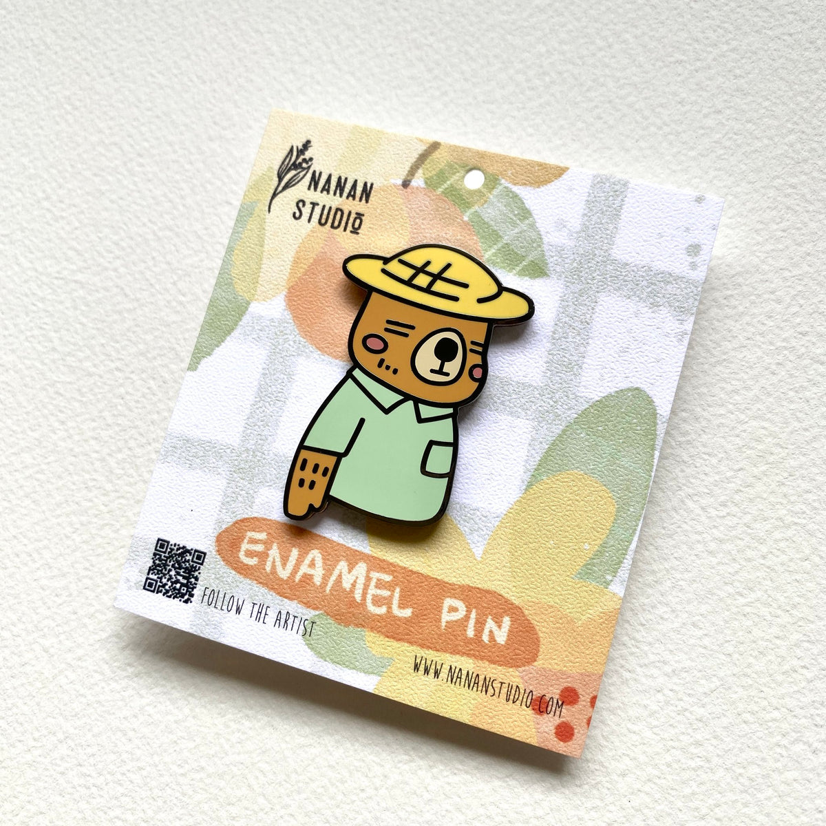 Mr. Otter enamel pin on its backing card, tilted to show the Nanan Studio logo and QR code