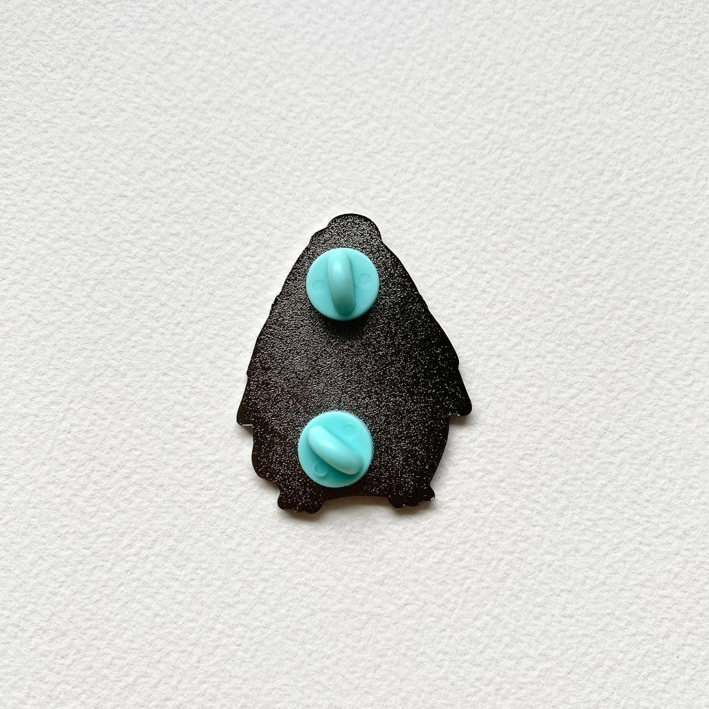 Back of the penguin postman enamel pin, black metal with two teal rubber pin backs